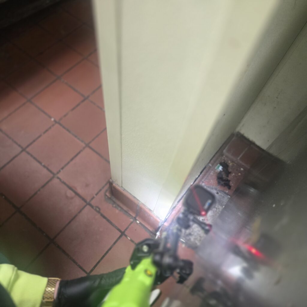 A Roberts Pest Control technician treating a pest entry point in a commercial kitchen in Hillsboro, MO 63050, St. Charles, MO 63301, and Potosi, MO 63664.