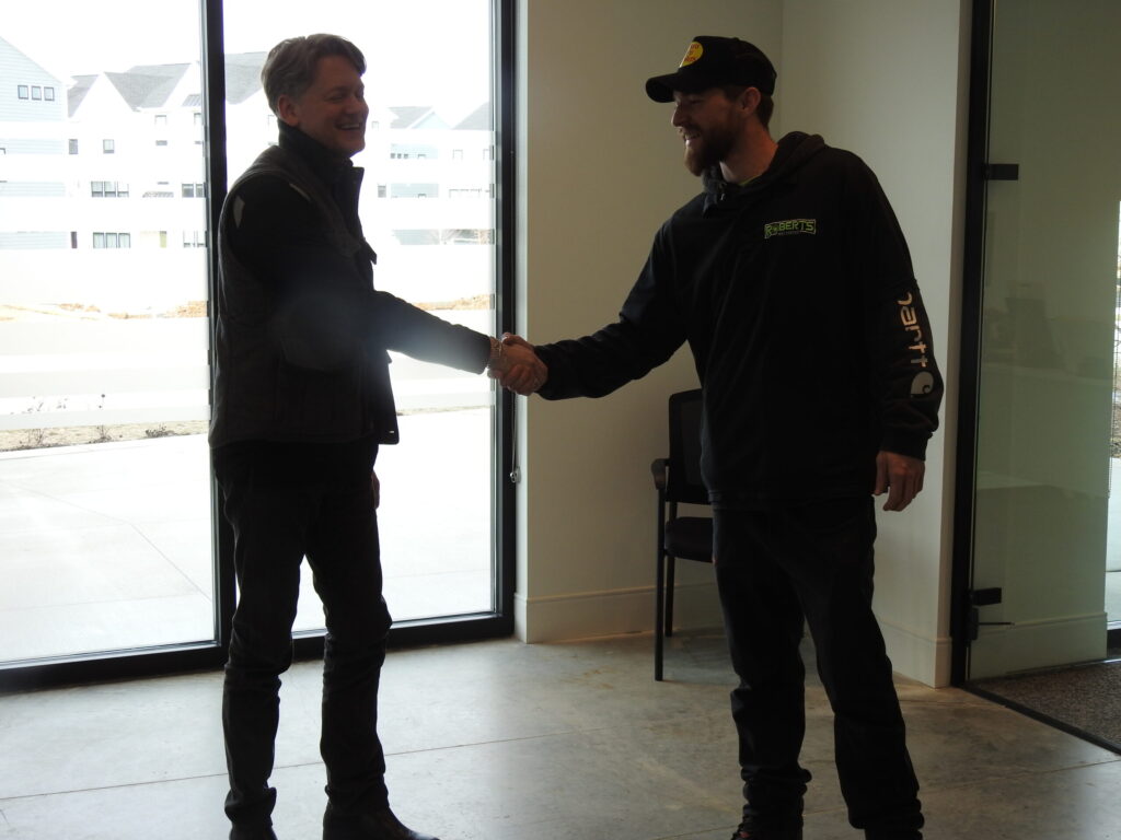 A satisfied business owner shaking hands with a Roberts Pest Control technician after a successful pest control service.