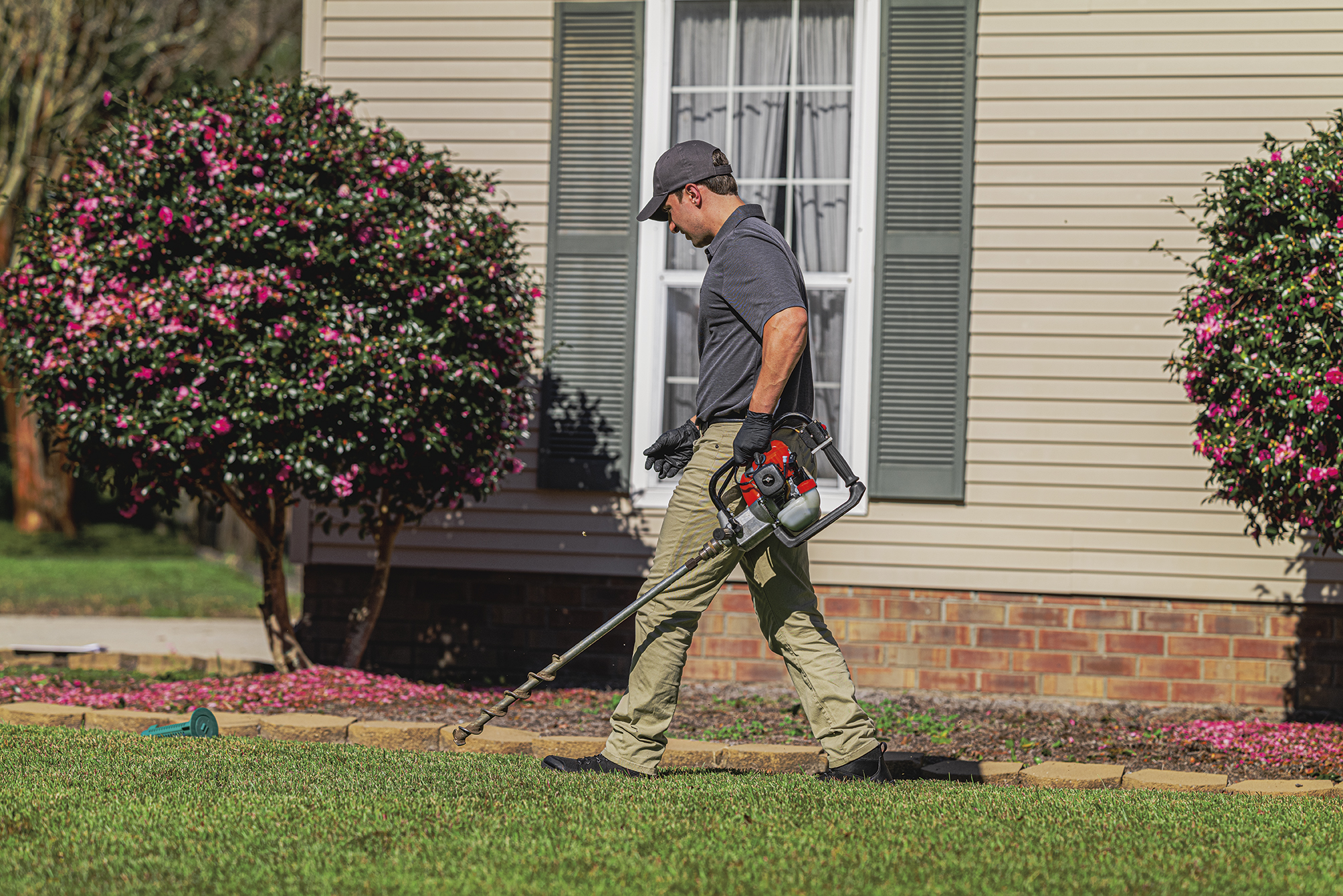 Roberts Pest Control certified technician installing Sentricon bait stations around St. Louis home perimeter