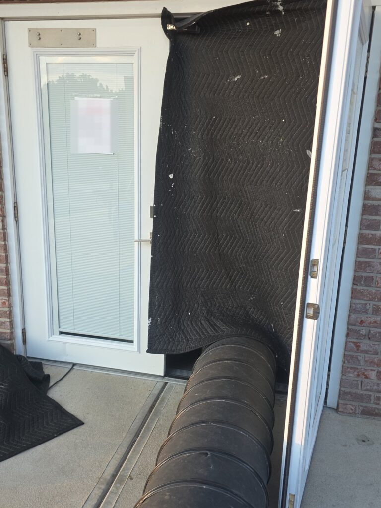Insulated heat treatment ducting sealed into a commercial building doorway with an insulating blanket during a Roberts Pest Control bed bug heat treatment