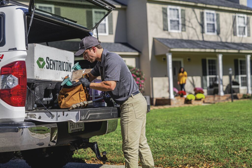 Pest control technician retrieving Sentricon termite equipment from a service truck