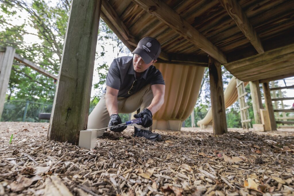 Pest control technician inspecting a home foundation and crawlspace area for signs of termite activity